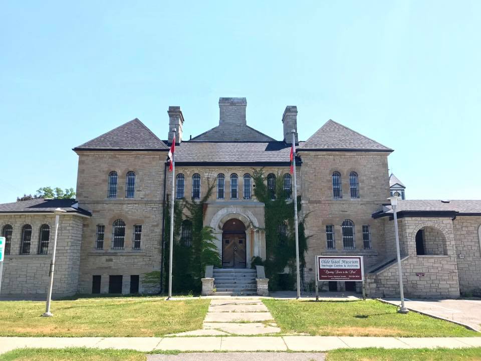 Exterior of a 19th-century Ontario stone gaol with barred windows and heavy masonry walls.