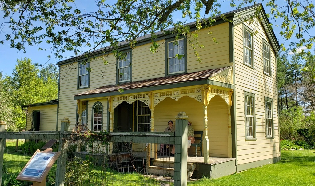 Beautiful yellow home with people sitting on the veranda